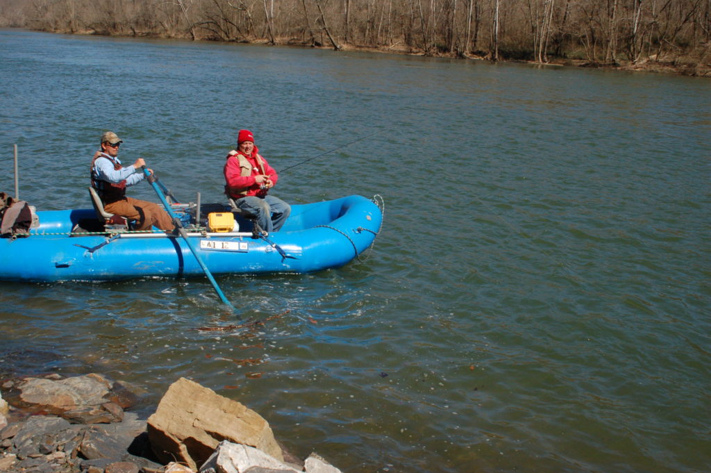 兩個男人在藍色的船上釣魚在深岩池附近的圖像