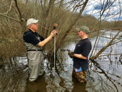 兩名三葉草發電站員工在河中的架子上放置巢穴的圖像