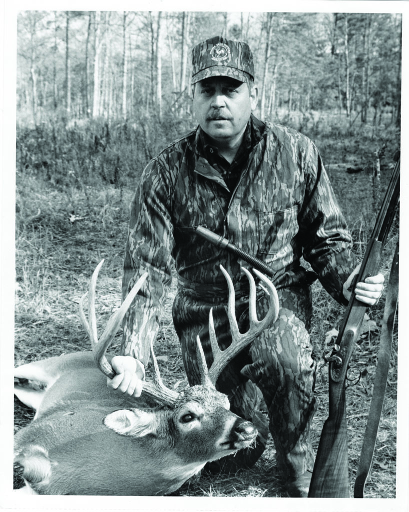 一張男子、鹿和鼻子裝載步槍的黑白照片