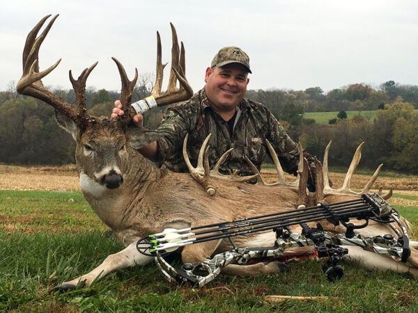 他用弓箭殺死的一隻公牛鹿旁邊的獵人的圖像