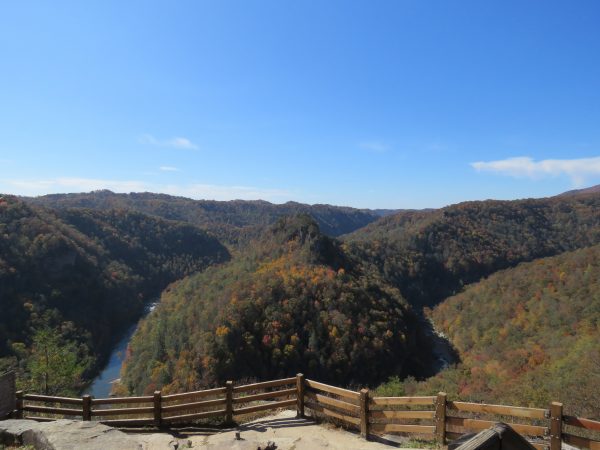 位於 Break 州際公園的美麗景色，它擁有美麗的秋季山脈，左下角有一條河流，前景的岩石頂上有木製圍欄。