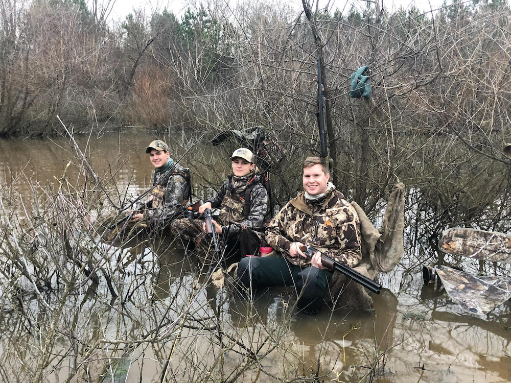 一群男人坐在水中的木頭上的圖像，這次他們找不到鴨子