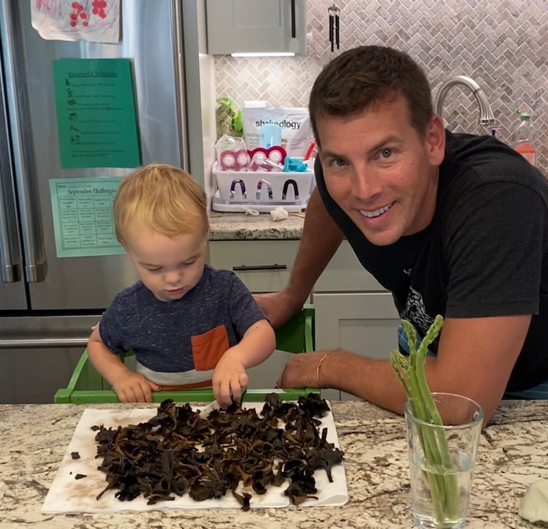 一個小男孩在一堆蘑菇旁邊和他的父親的圖像