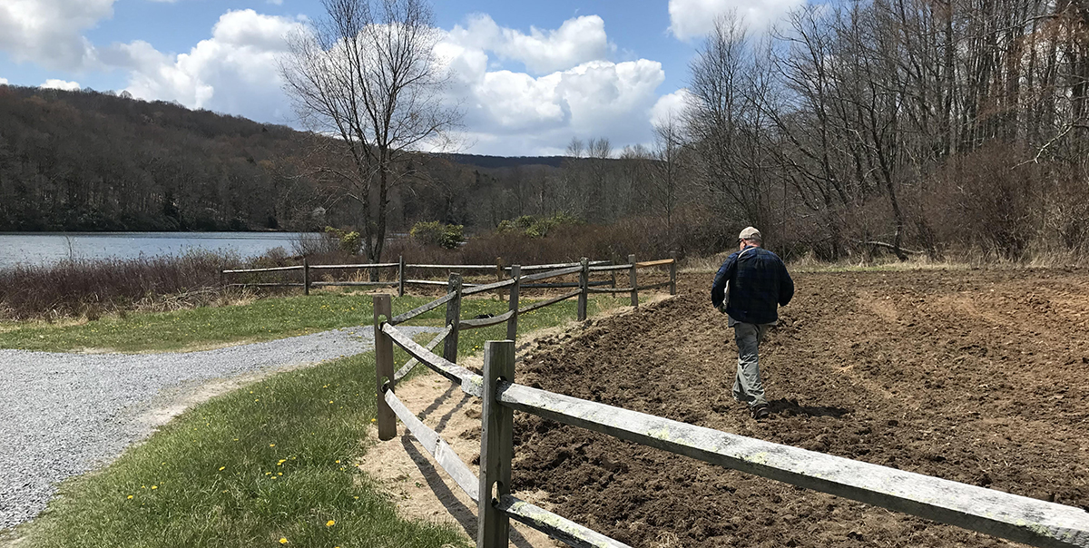 一名 DWR 工作人員正在向圓盤土壤上分發肥料和種子。