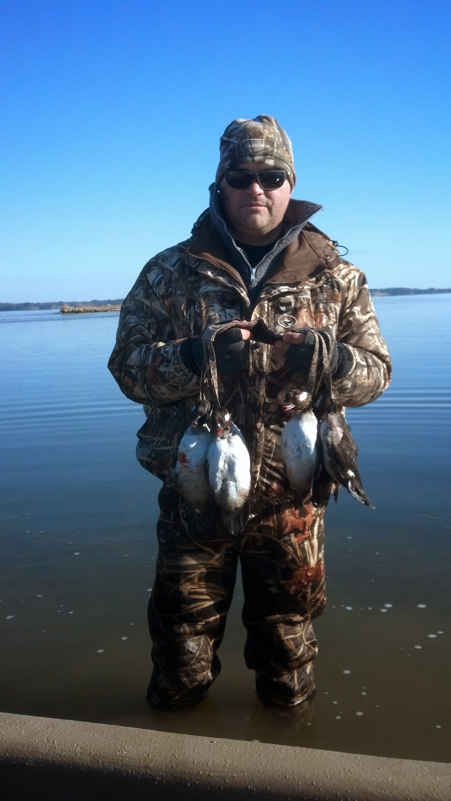 一個男人在冰水中抱著一堆死鴨的圖像