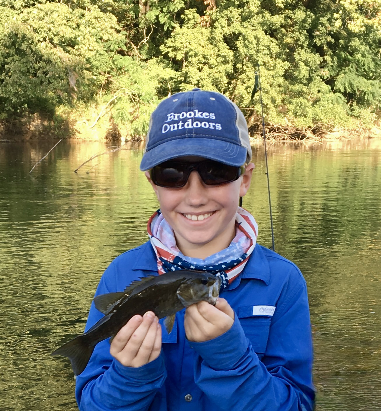 一張男孩拿著一隻小嘴巴，在後面微笑著一條河流的照片。