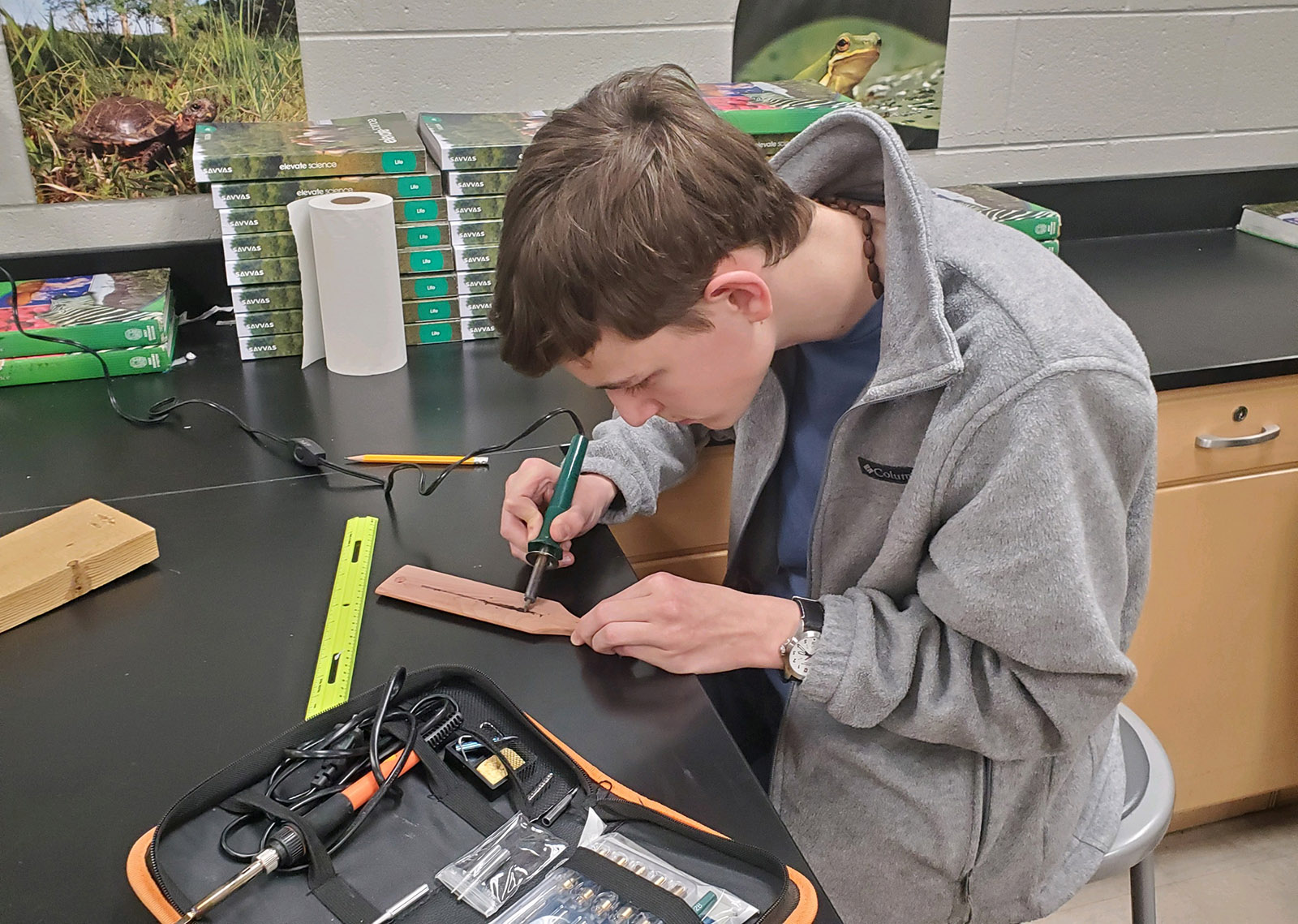 一位年輕男子在工作桌上使用燃木工具在火雞叫槳上的照片。