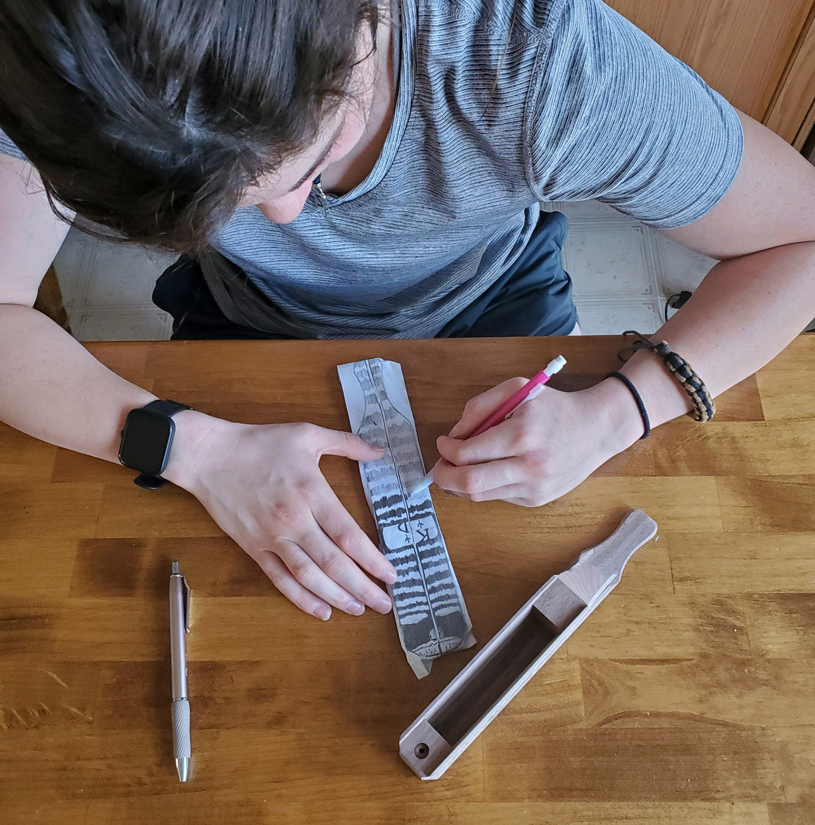 一張女孩在紙上描繪圖案的照片，並坐在她旁邊坐在桌子上的槳火雞呼叫。