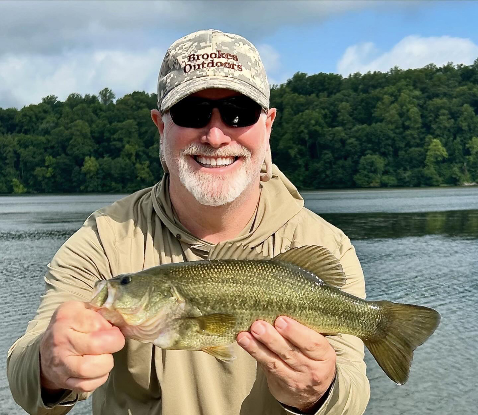 一個男人在河前抱著一隻大的烏貝。