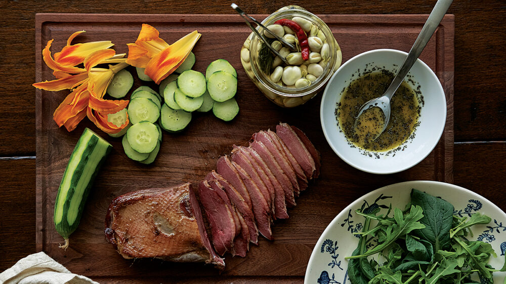 煙熏鵝、百合、黃瓜、芝麻菜和醃製法瓦豆的圖像