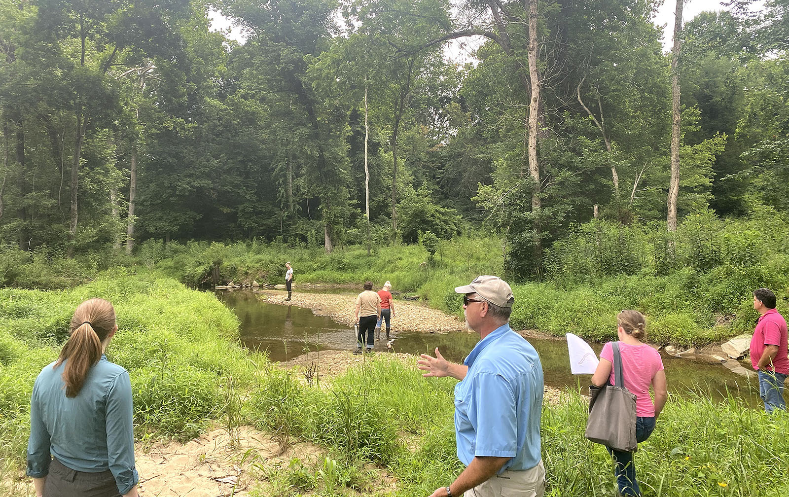 一群人聚集在一條河畔，討論。
