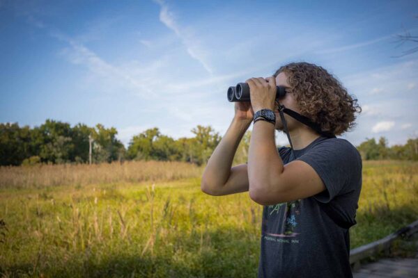 一個穿 T 恤的男人拿雙筒望遠